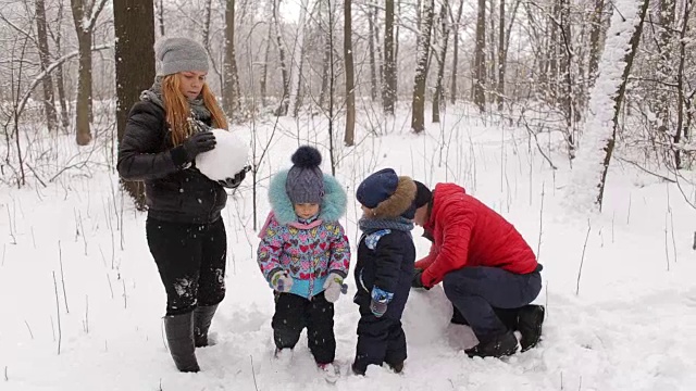 年轻的家庭和孩子们在堆雪人。视频素材