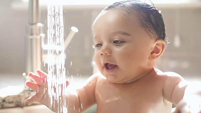 婴儿在水槽洗澡和微笑看向别处视频素材