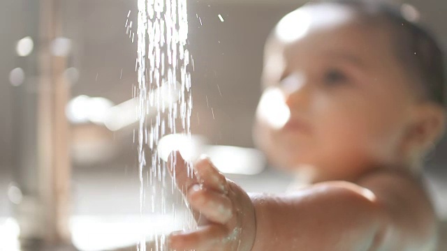 婴儿把手伸向水龙头水架，专注于脸视频素材