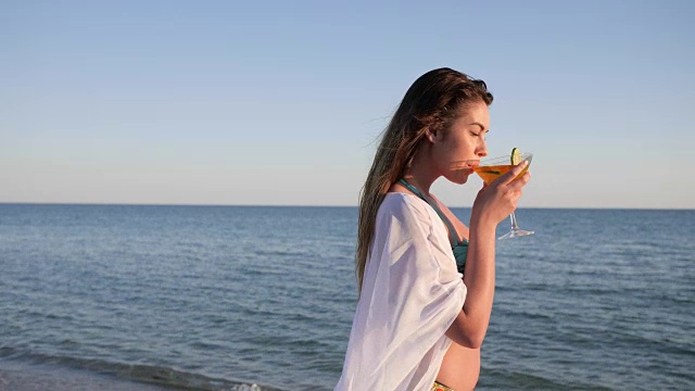 性感女孩沿着海滩模特，夏天在海上休息，年轻女性喝鸡尾酒视频素材