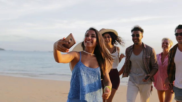 女孩用手机欢迎人们在海滩上自拍，快乐微笑的男女朋友视频素材
