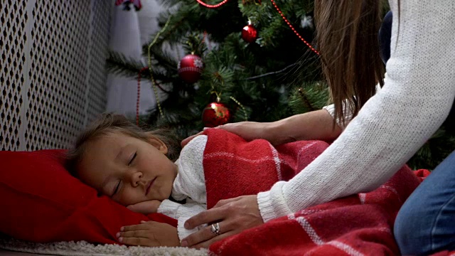 可爱的小女孩早上睡在圣诞树下视频素材