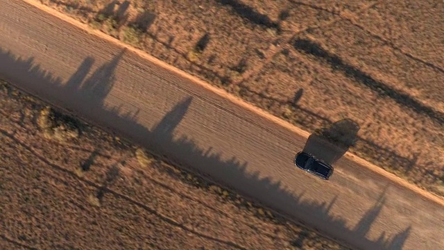 空中特写:飞过一辆黑色SUV，行驶在尘土飞扬的沙漠道路上视频素材