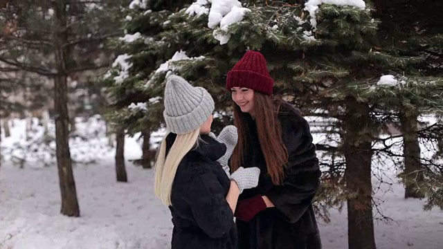 两个快乐的女朋友在冬季公园散步。视频下载