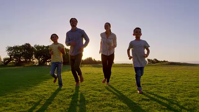 一个年轻的白人家庭跑向公园里移动的摄像机视频素材