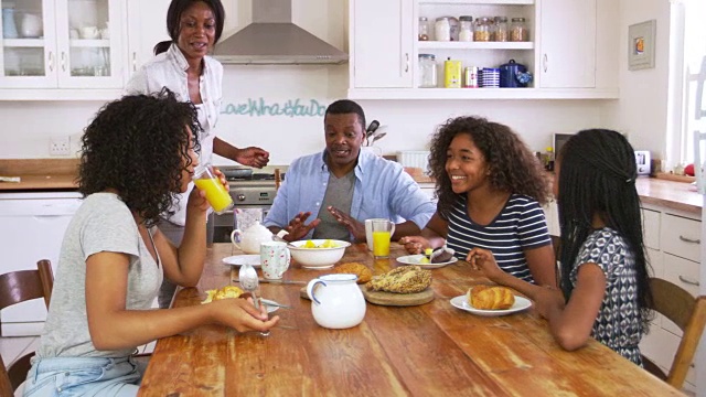 一家人和十几岁的孩子在厨房吃早餐视频素材