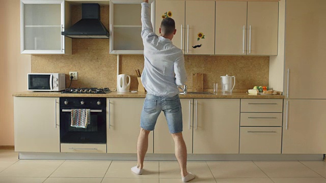 英俊的年轻有趣的男人在厨房跳舞在家里的早上和有乐趣的假期视频素材