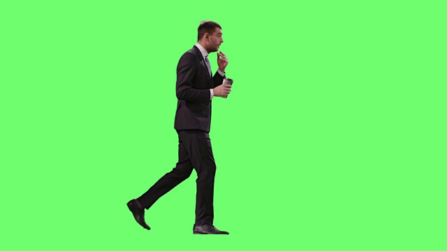 疲倦的商人在一个模型的绿色屏幕在背景中走着咖啡西装。视频素材