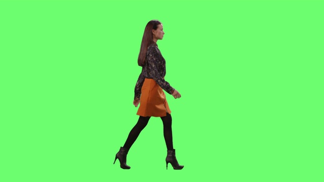 时尚的年轻黑发优雅地走。在一个模型的绿色屏幕在背景。视频素材