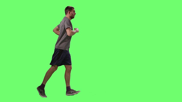 背景中一个穿着t恤的男人在绿色屏幕模型上慢跑。视频下载