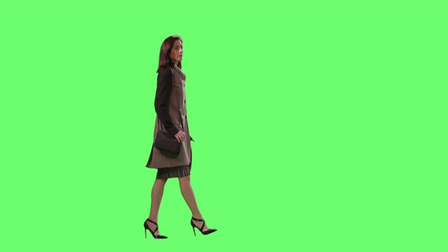 休闲黑发女性是走在一个模型的绿色屏幕在背景。视频素材
