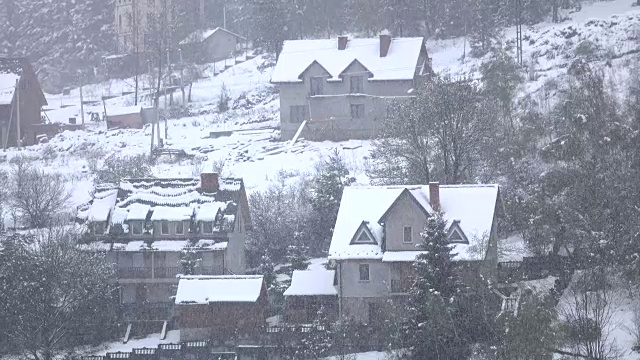 雪花静静地飘落在绿树成荫的山村视频素材