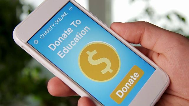 一名男子通过智能手机上的慈善应用为教育进行在线捐赠视频下载