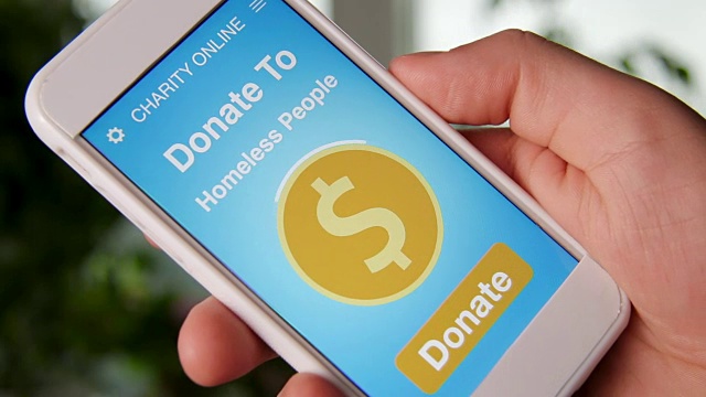 一名男子通过智能手机上的慈善应用为无家可归的人在线捐款视频素材