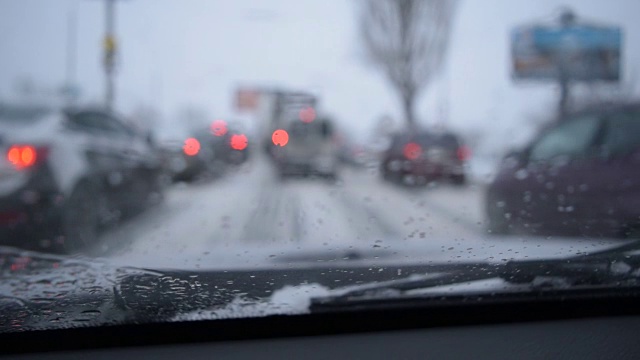 透过挡风玻璃看散焦的场景在下雪的城市道路视频下载