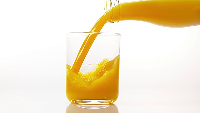 在白色背景下，将橙汁倒入玻璃中，慢动作4K视频下载