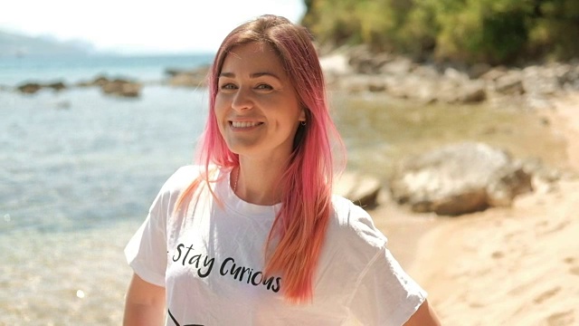 一个美丽的女人的肖像与粉红色的头发在一个夏天的海滩视频素材