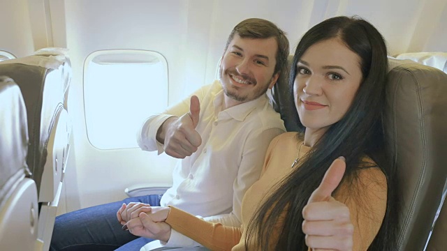 飞机上一对快乐的夫妇竖起大拇指视频素材