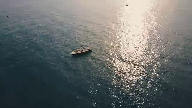鸟瞰图快艇在一个阳光明媚的日子在平静的水附近的海岸。太阳在水面上的反射。视频素材