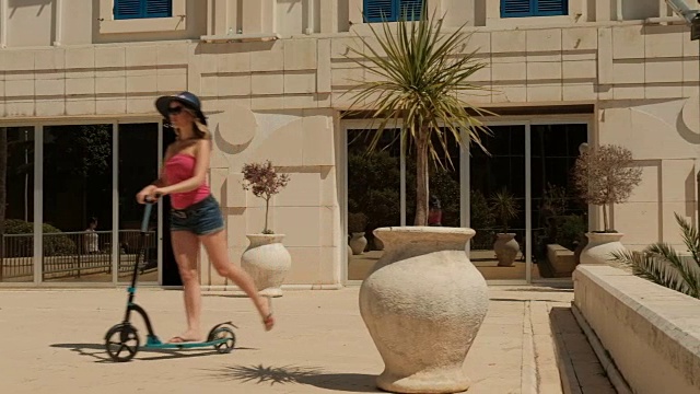 夏日里，年轻女子在户外骑踏板车视频素材