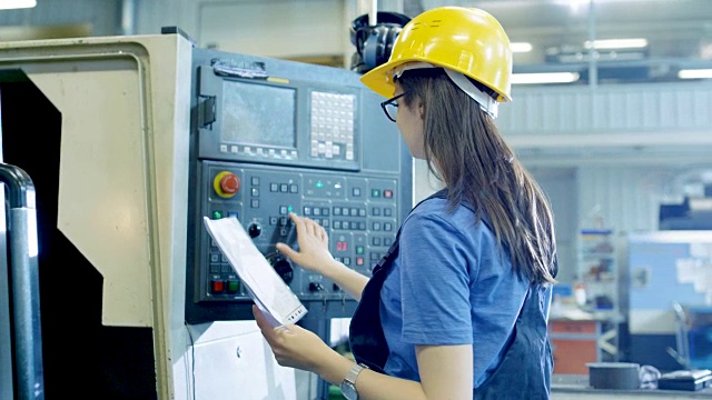 专业的女操作员在控制面板的帮助下设置/编程数控机床。可见大工业工厂。视频素材