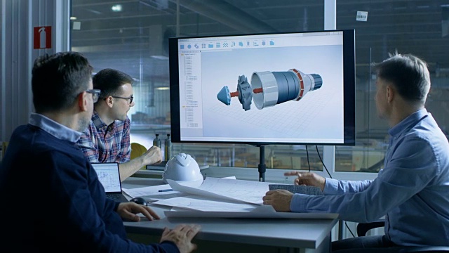 工业工程师小组讨论三维涡轮/发动机部件设计显示在演示显示。在背景工厂被看到。视频素材