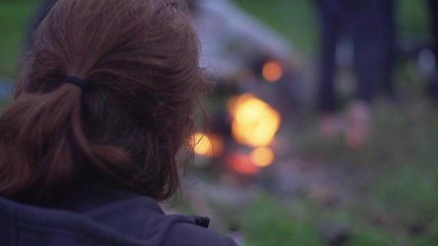 在炉火旁取暖的女人。野营视频下载