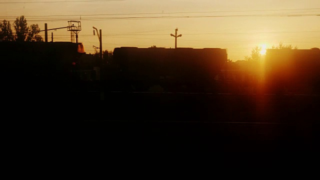 黎明时从火车窗口看到的景象。有树木、车站建筑和马车的剪影视频素材