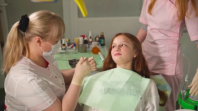牙科医生在钻孔后为小女孩病人洗牙。工作助理视频下载