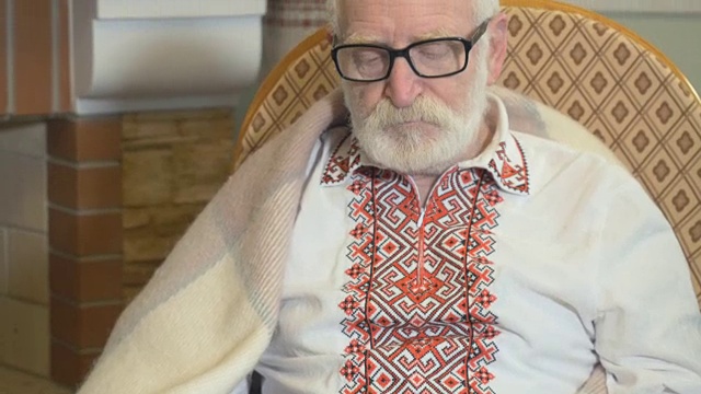 穿着传统服装的老人手里拿着一张纸，坐在摇椅上视频素材