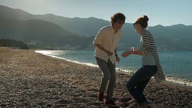 一对夫妇在海滩上玩日落舞蹈视频素材
