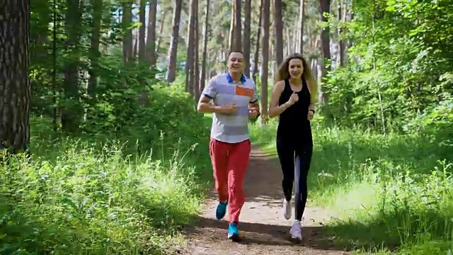 一个阳光明媚的夏日，一个男人和一个女人穿着跑鞋在公园的小路上跑步，夫妻在运动中交谈视频素材