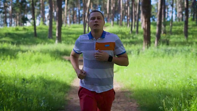 一个成年男子跑过公园区域，为了让自己的身体保持良好的体型，他自信地向前跑视频素材