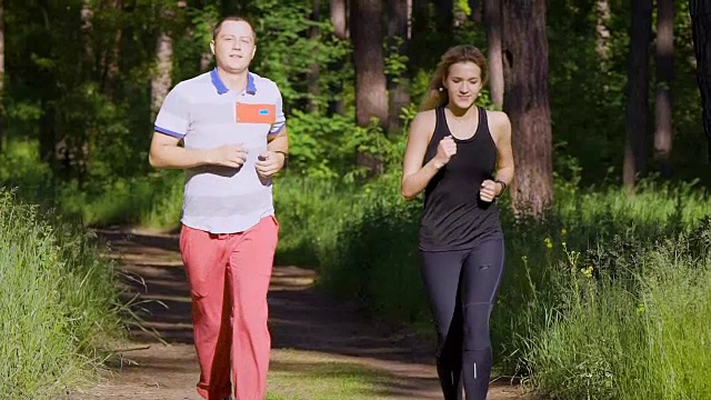 慢镜头拍摄一对夫妇在公园里跑步，夫妻二人积极跑步，以保持良好的身体状态视频素材