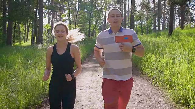 慢镜头拍摄的一对年轻夫妇，他们在公园里活跃地度过了一天，情侣们在夏天穿着运动服在公园里跑来跑去视频素材