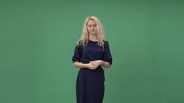 美丽的金发女子在蓝色的裙子触摸虚拟屏幕，色度键绿色的屏幕背景视频素材
