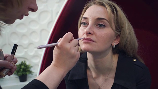 美丽的金发女人在她的嘴唇化妆的特写肖像。视频素材
