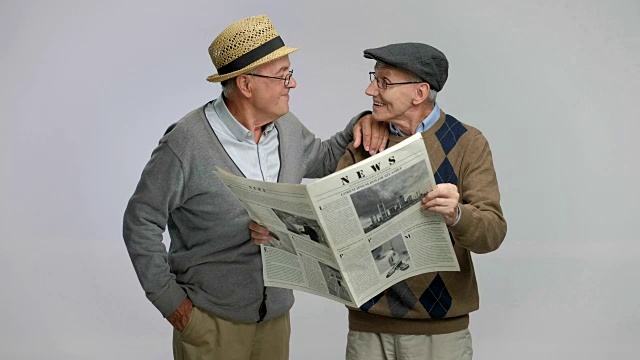 两个老人一边看报纸一边聊天视频素材