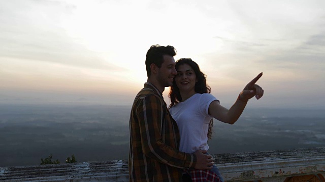 一对情侣来到山顶拥抱，女孩伸出手指，游客男女欣赏风景视频素材