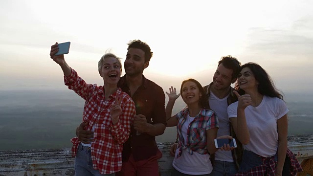 日出时分，人们在山顶自拍，朋友群游客一起对着手机摆姿势视频素材