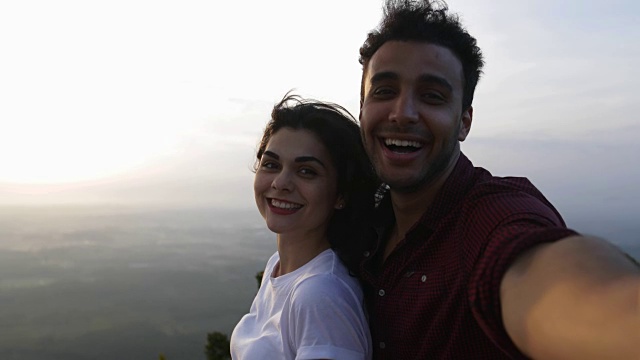 一对夫妇在山顶拍摄日出自拍，拉丁男人和女人幸福的微笑视频素材