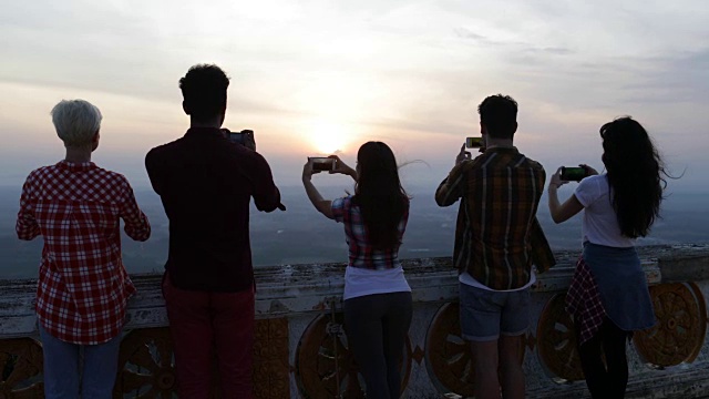 人们在山顶行走，用手机拍摄日出景观，游客后视镜视频素材