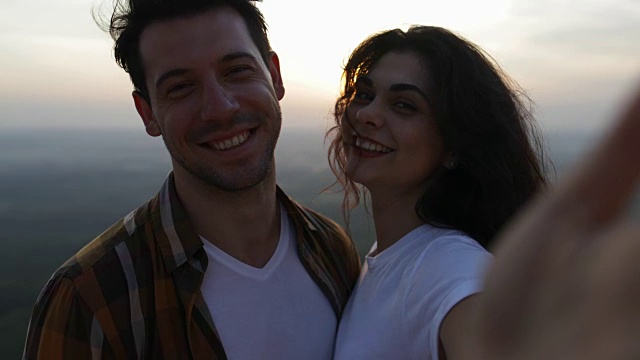 一对情侣在山顶日出自拍，游客男女开心地微笑着视频素材