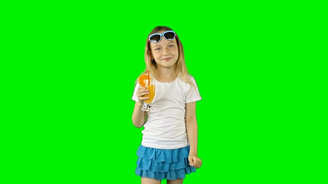 穿着白色t恤的年轻女孩调情，喝玻璃杯里的橙汁。快乐女孩用吸管喝橘子鸡尾酒。剪辑包含纯绿色而不是alpha通道。视频素材