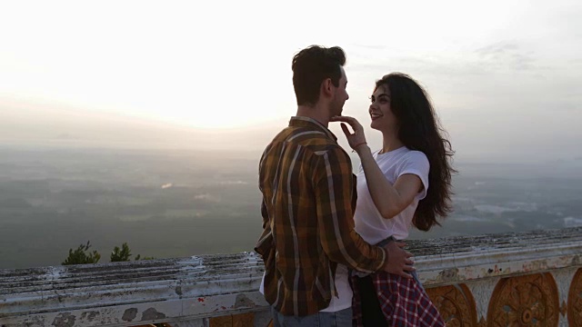 女孩牵着男人的手去山顶，游客夫妇在日出时拥抱视频素材