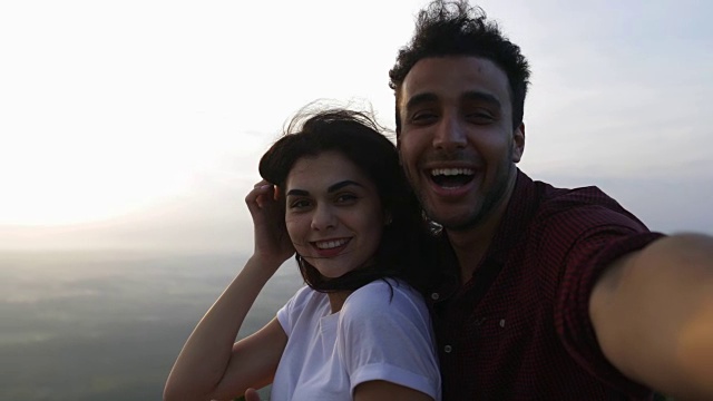 一对夫妇在山顶上拍摄日出自拍照片，西班牙男人和女人幸福的微笑视频素材