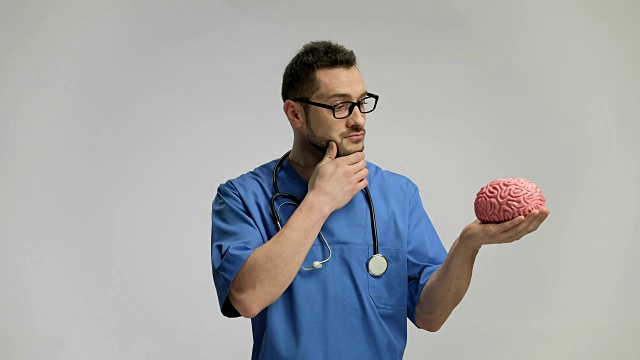 沉思的医生在看一个大脑模型视频下载