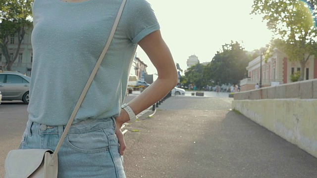 服装细节:一个穿着牛仔裤和t恤的年轻女子，背景是一个夏天的城市视频素材