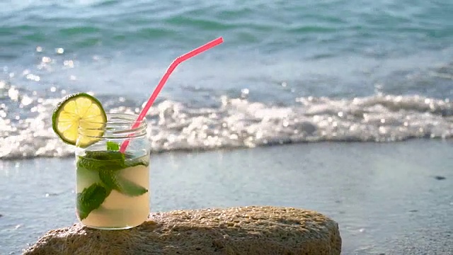 近距离的莫吉托酒精鸡尾酒站在沙滩上的沙子视频素材