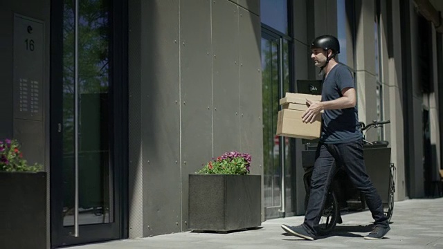 帅气的自行车快递员卸下他的货物自行车视频素材